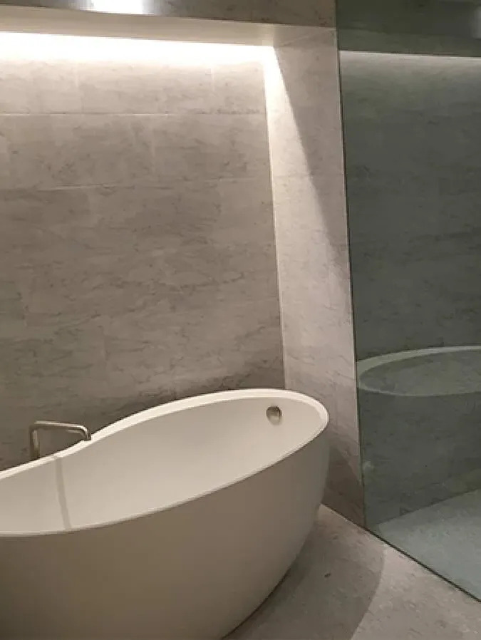 Freestanding tub with stone surround and cove lighting
