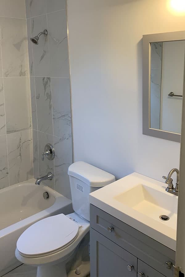 Marble-tiled tub surround with shaker vanity and framed mirror