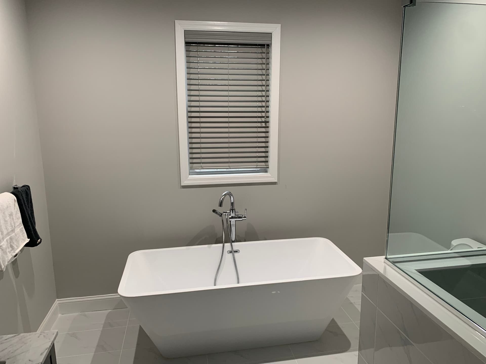 Modern freestanding soaking tub with chrome floor-mount faucet and glass shower enclosure