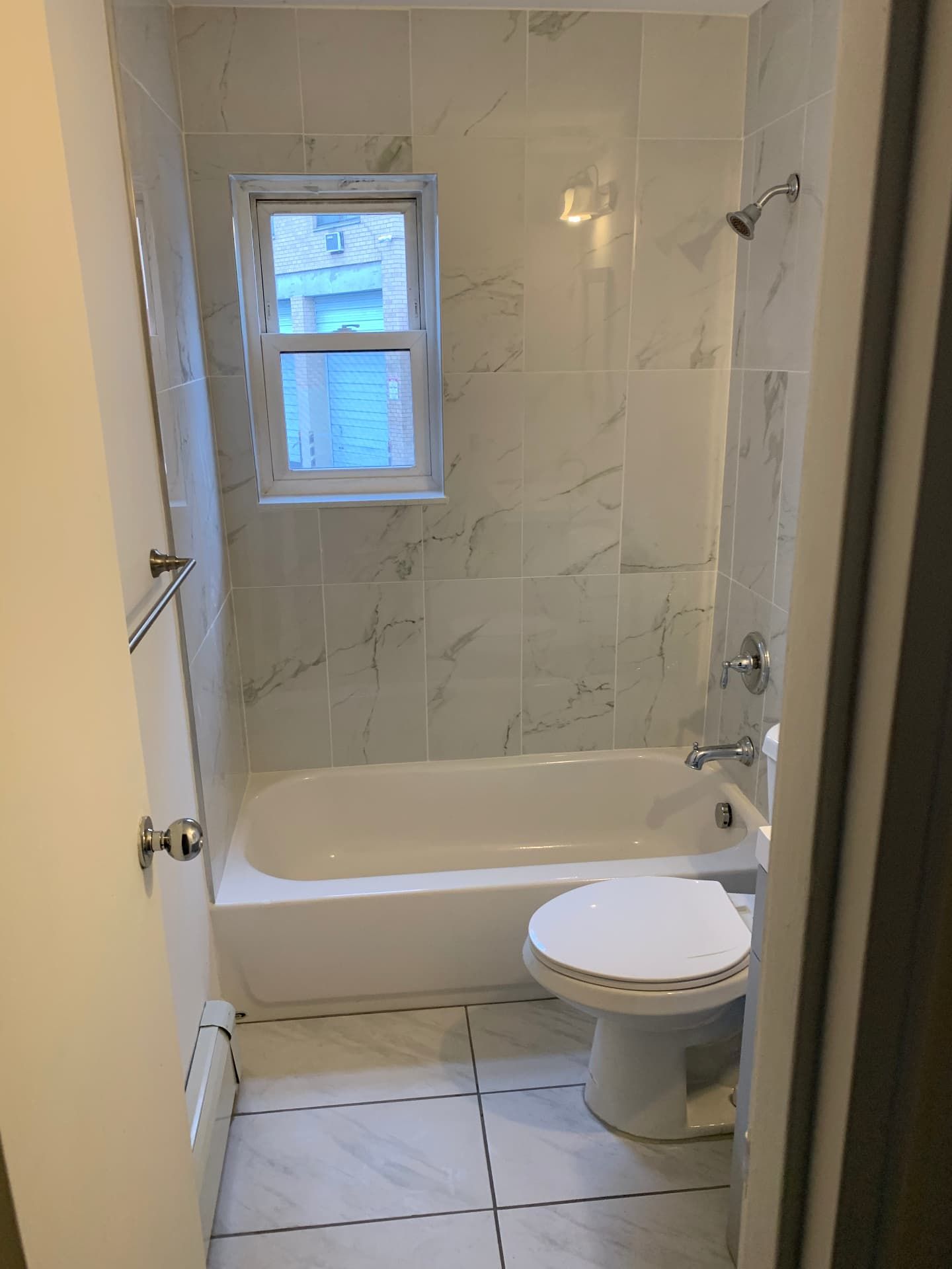 Renovated bathroom with marble-look tile surround and clean white finishes