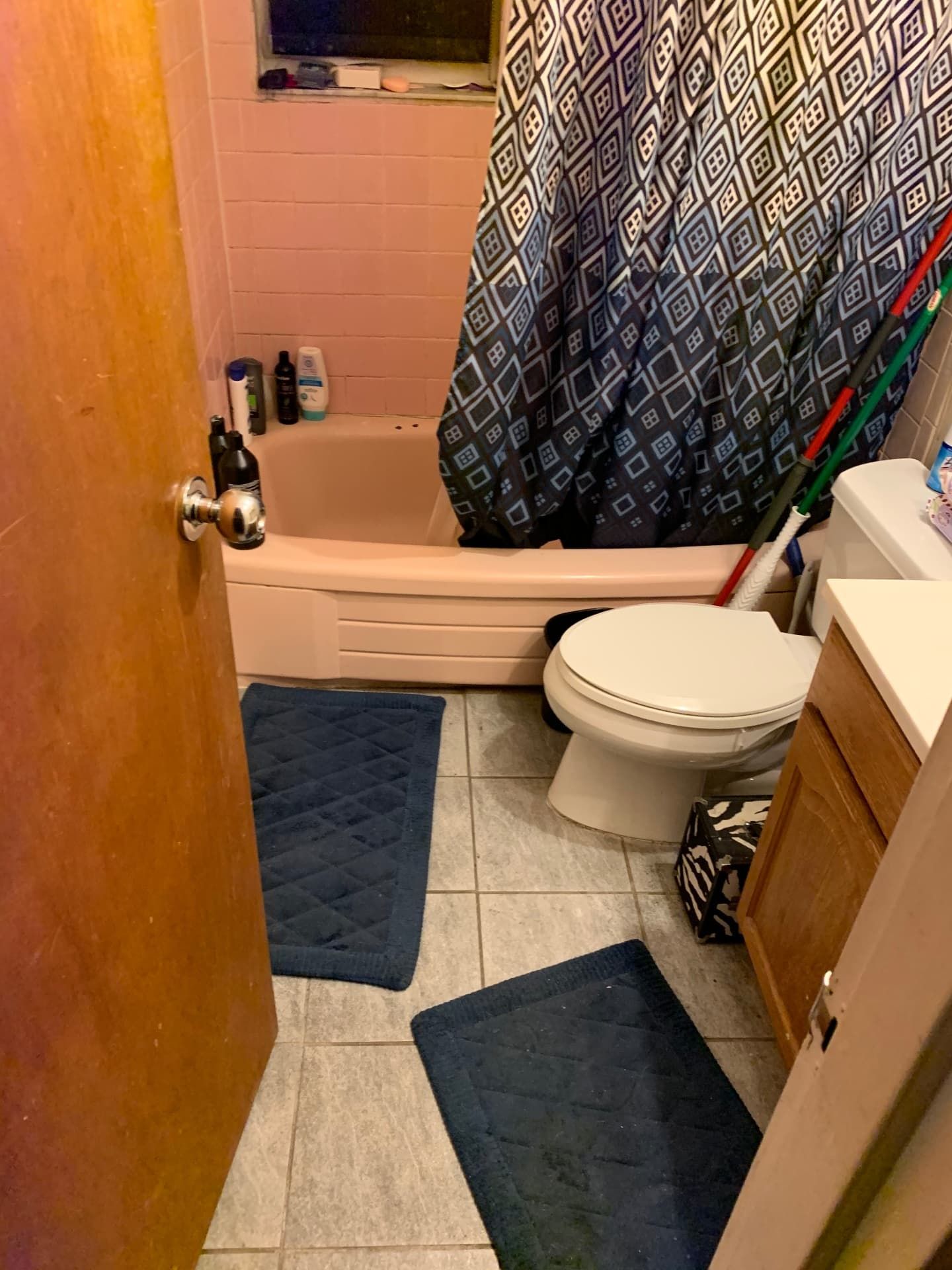 Dated bathroom with pink tile tub surround and old fixtures before remodel