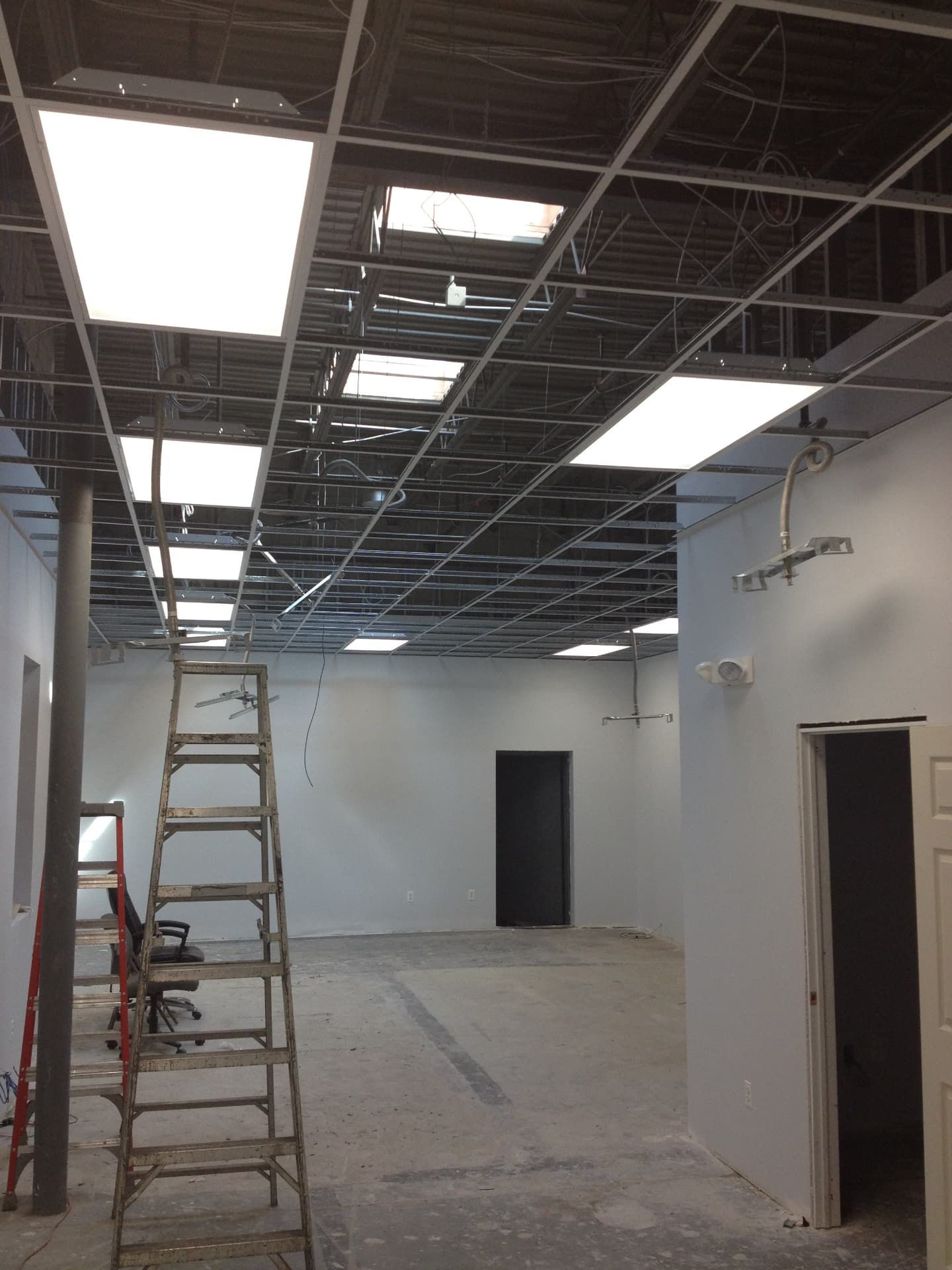 Commercial build-out in progress with drop ceiling grid and lighting installation