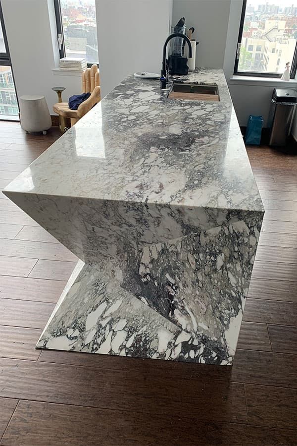 Sculptural marble island with angled waterfall legs