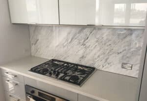 Full-height marble backsplash with gas cooktop