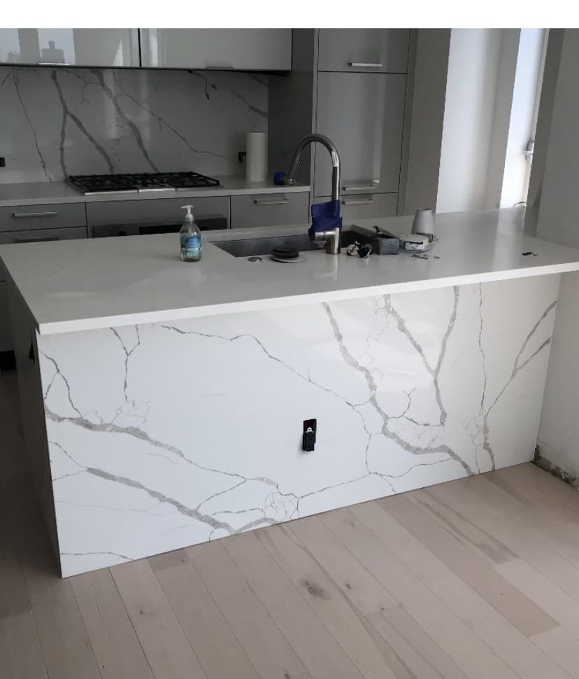 Calacatta quartz waterfall island with matching slab backsplash in modern kitchen
