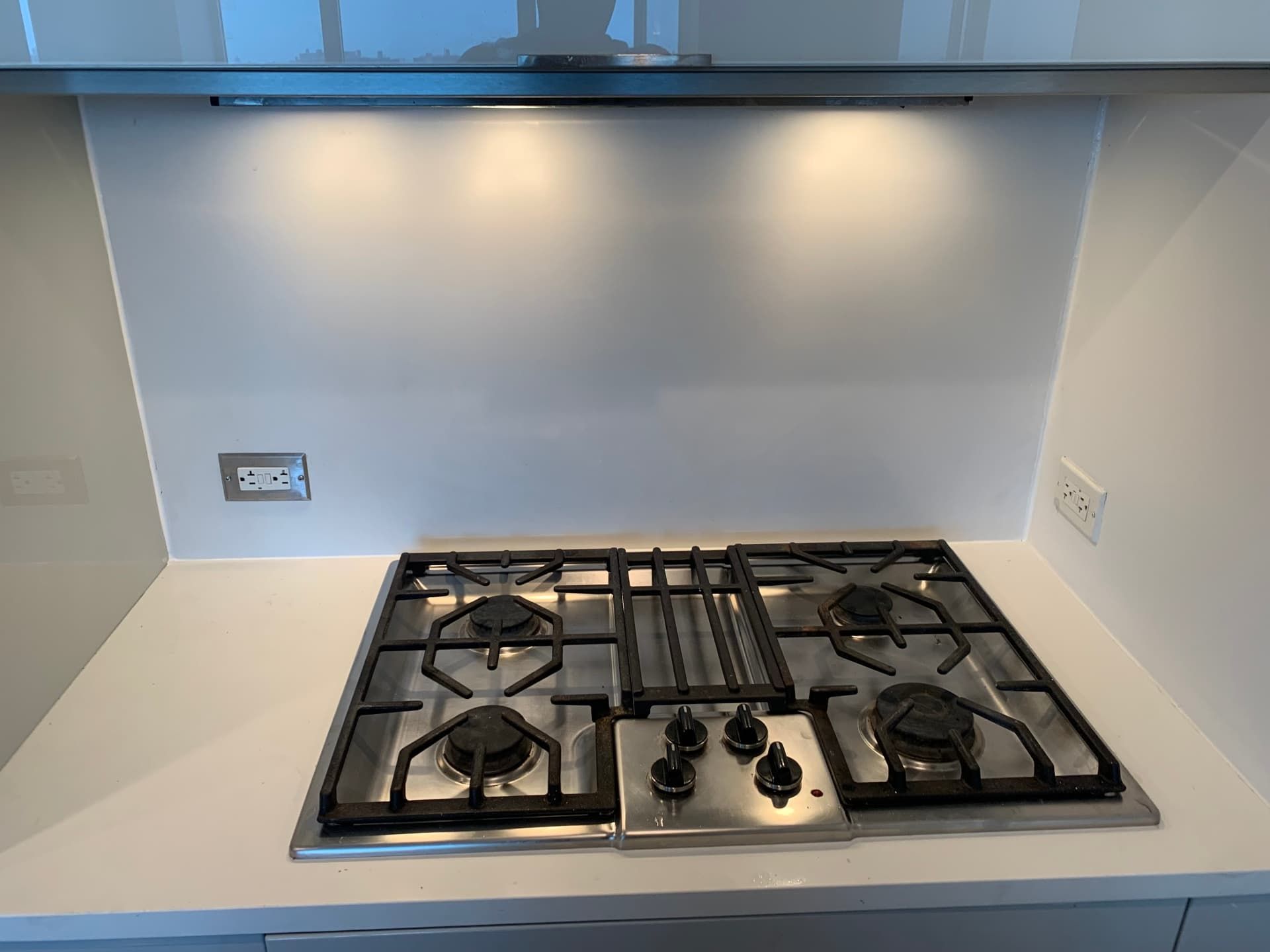 Quartz countertop with stainless gas cooktop and clean white backsplash