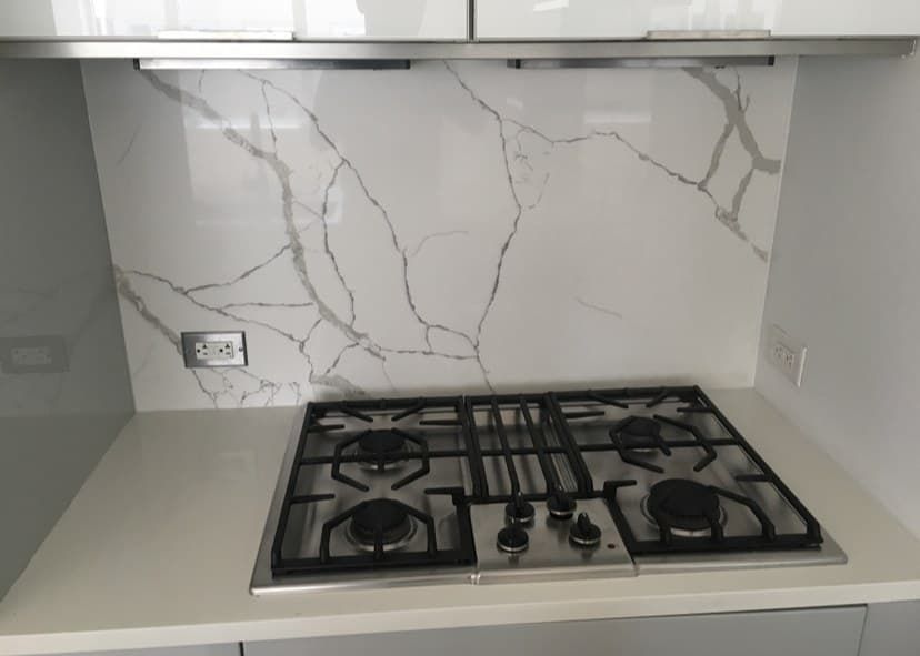 Calacatta quartz full-height backsplash behind stainless gas cooktop