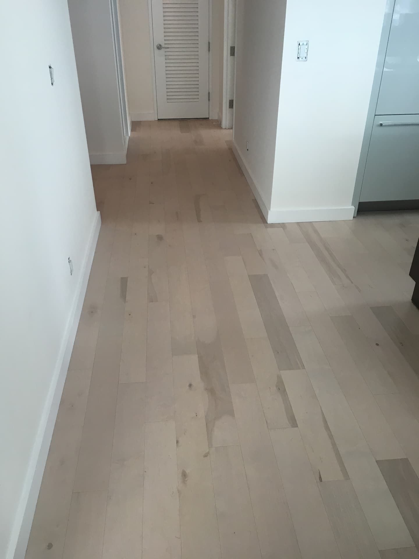 Light wide-plank hardwood hallway with white walls