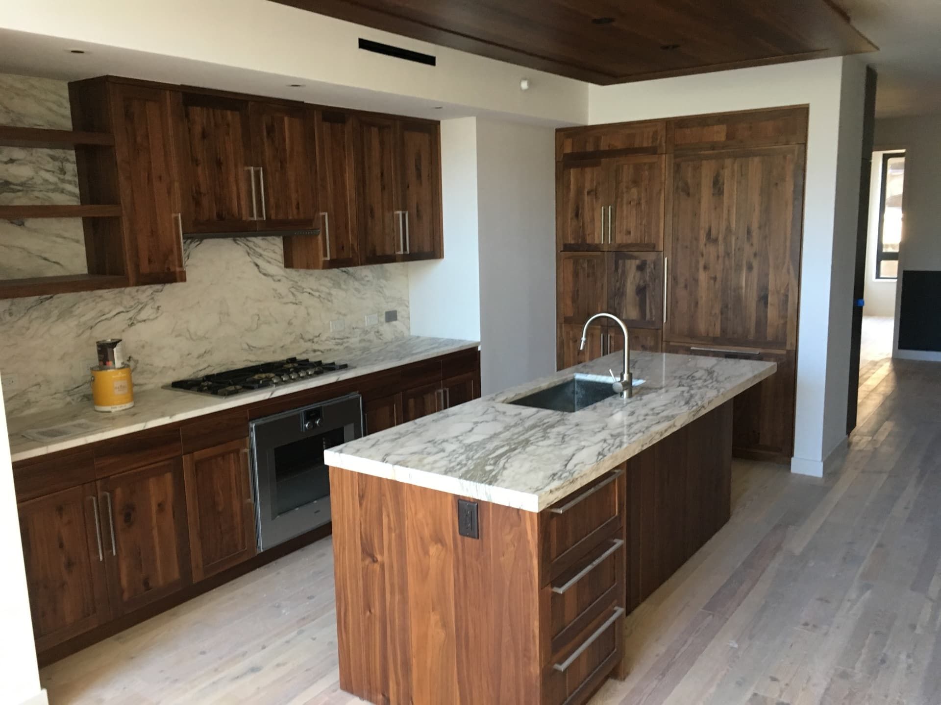 Walnut cabinetry kitchen with marble waterfall island and slab backsplash