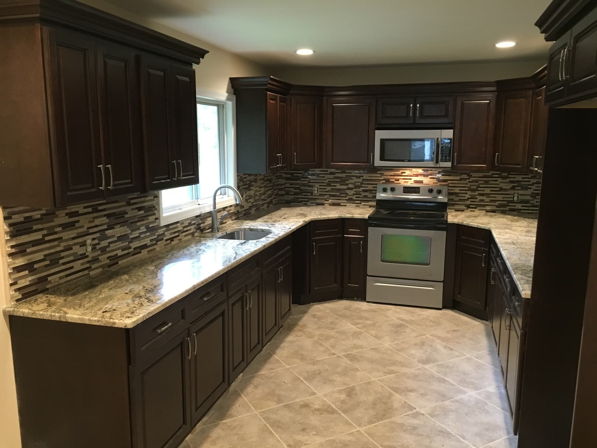 Espresso cabinetry kitchen with granite counters and glass mosaic backsplash