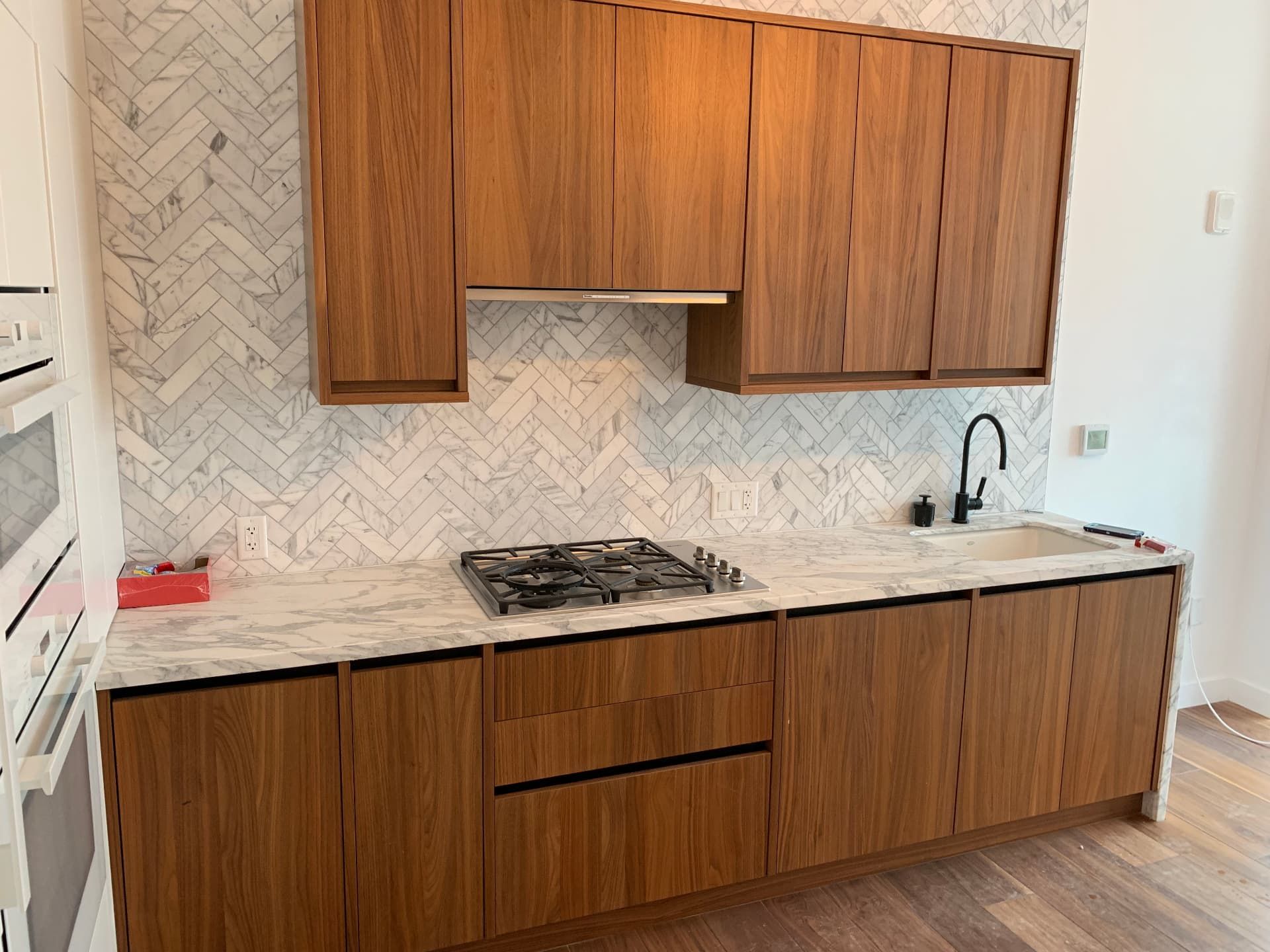 Walnut flat-panel cabinets with marble counters and herringbone backsplash