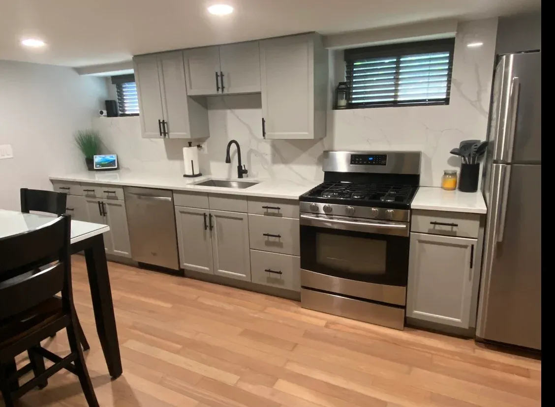 Basement kitchen after remodel with gray cabinets and quartz backsplash