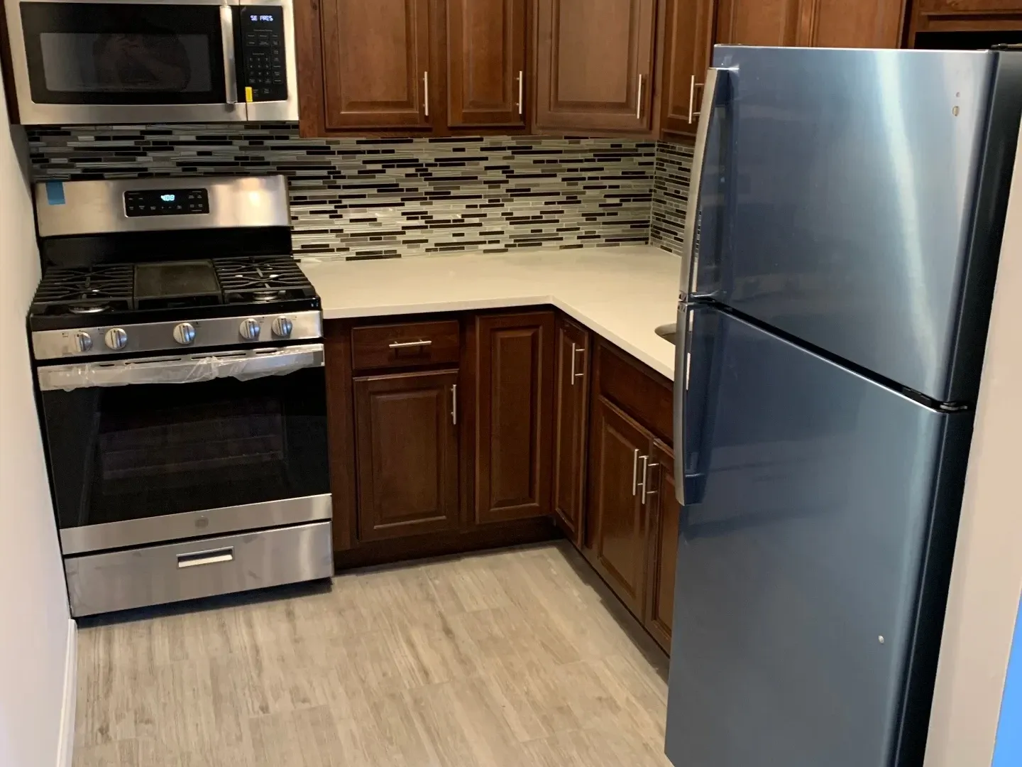 Renovated kitchen with cherry cabinets, tile backsplash, and stainless appliances