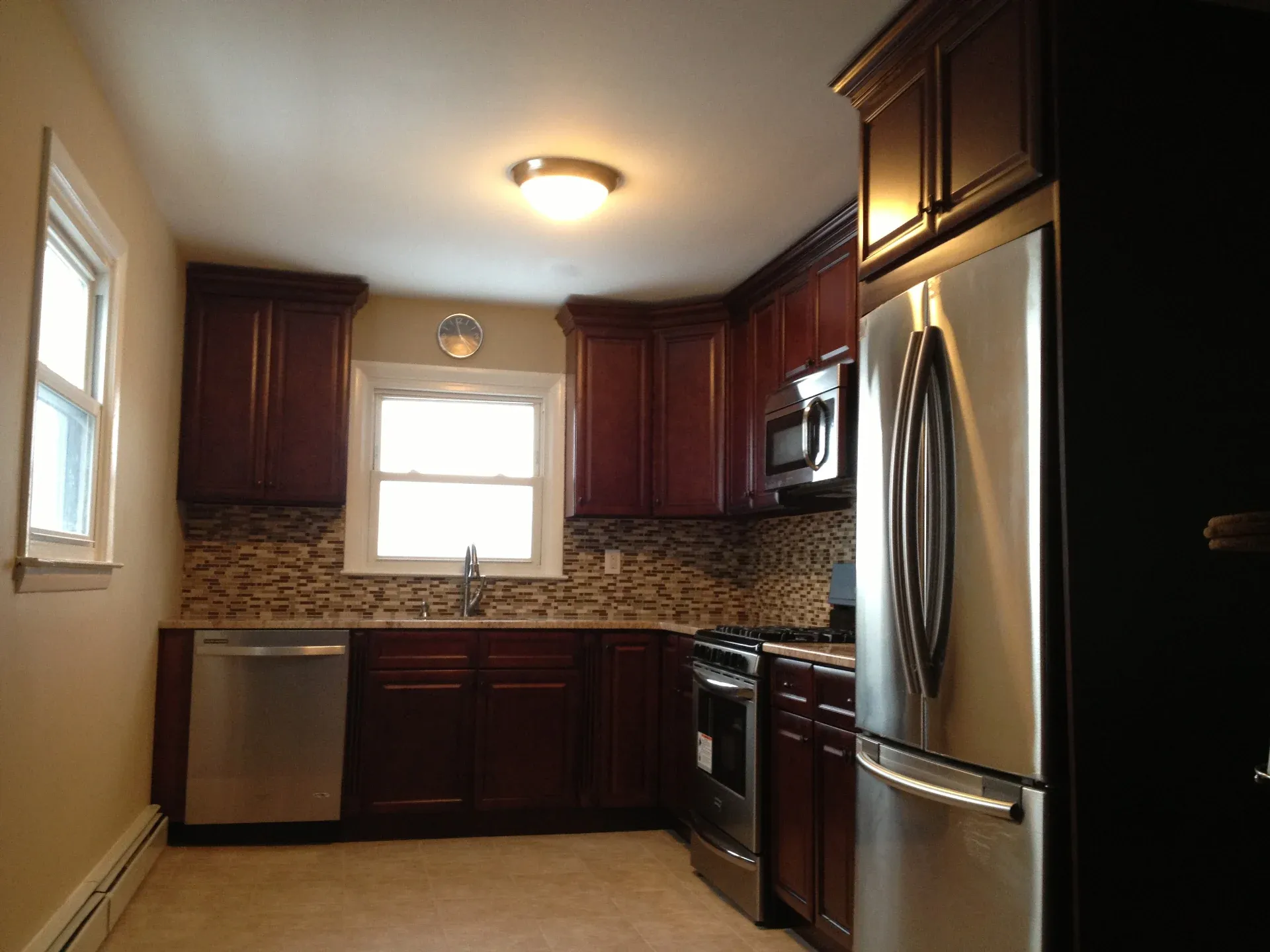 Renovated kitchen with cherry cabinets, mosaic backsplash, and stainless appliances