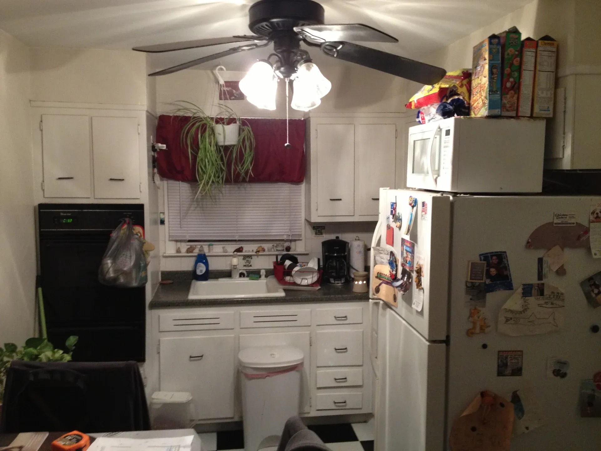 Cluttered white kitchen with old cabinets and appliances before remodel