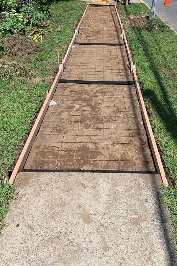 Long concrete walkway formed with wood and rebar, prepped for pour