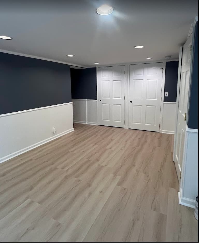 Navy and white wainscoted basement with luxury vinyl plank floors
