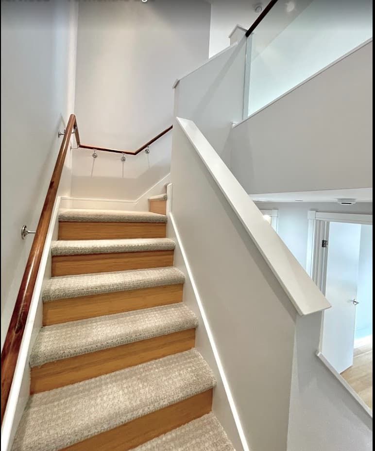 Bright white painted stairwell with modern glass railing