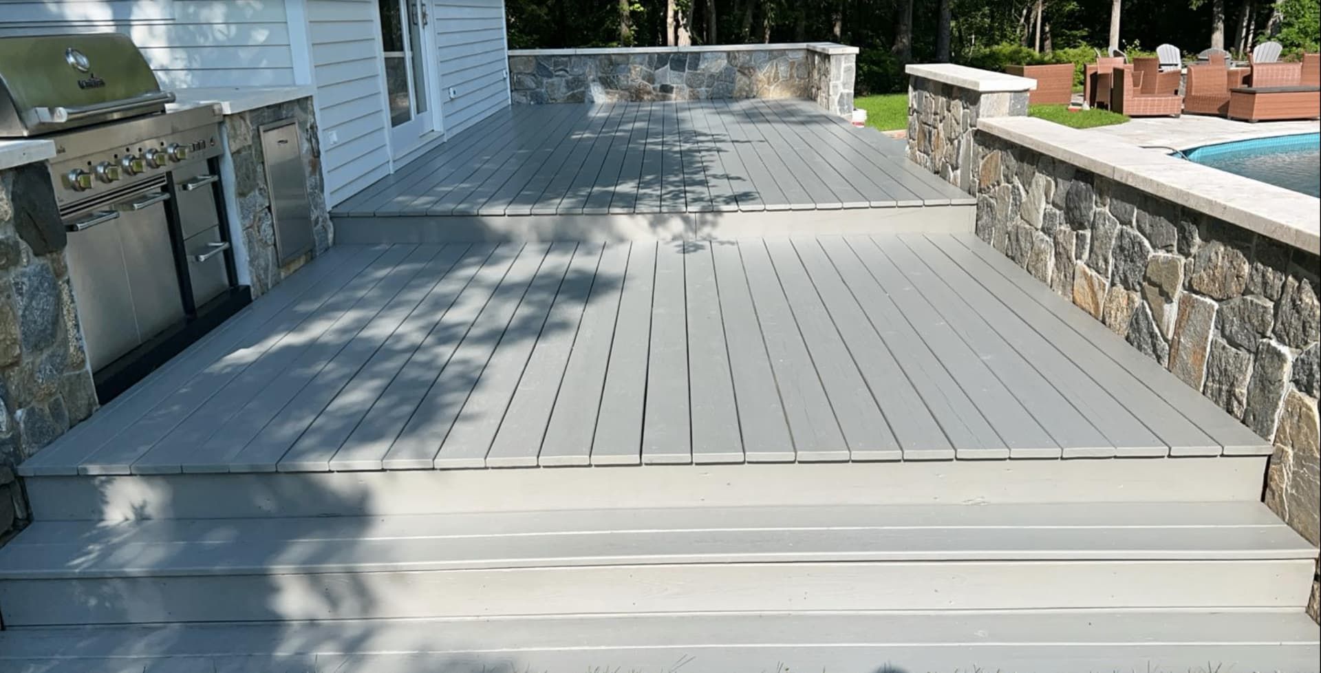 Freshly stained outdoor deck with stone walls and grill station